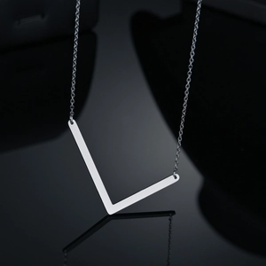 Vue détaillée du collier pendentif en V argenté poli sur une surface noire réfléchissante