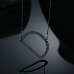 Gros plan détaillé du collier avec pendentif lettre D noire et finition métal sombre