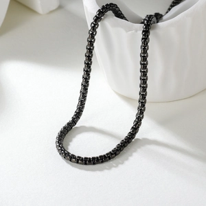 Polished gunmetal stainless steel box chain necklace displayed on a ceramic bowl