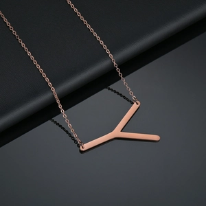 Vue macro du pendentif lettre Y en or rose poli sur une fine chaîne maille jante