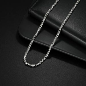 Detailed macro view of 2mm silver stainless steel box chain link necklace on dark background