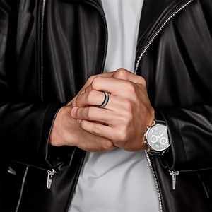 Detail view of men's black titanium steel ring with silver frosted inlay worn by model