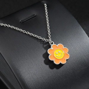Collier en acier titane avec pendentif fleur sourire orange sur support noir