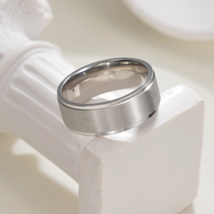Bague pour homme en acier inoxydable brossé mat avec bords polis sur socle blanc