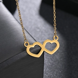 Polished gold double heart pendant necklace on a textured black jewelry box