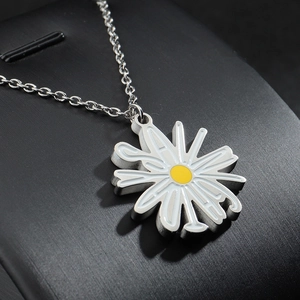 Collier avec pendentif marguerite en acier inoxydable sur un support d'exposition noir