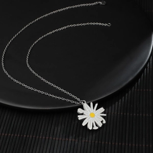 Collier long en acier titane avec pendentif marguerite blanche sur support noir