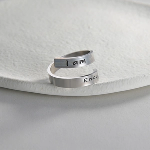 Minimalist silver stainless steel open ring with I Am Enough engraving on rock surface