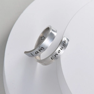 Silver stainless steel open ring with I am Enough engraving on brushed metal surface