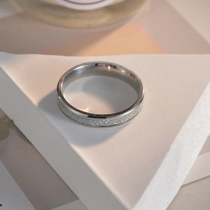 Macro detail of a 4mm silver titanium ring with meteorite texture on a white stone base