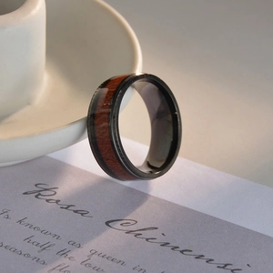 Men's black titanium steel ring featuring natural red koa wood inlay and polished edges