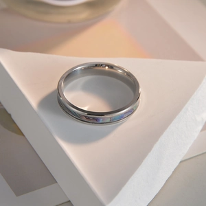 Detailed shot of 4mm titanium steel ring with iridescent shell inlay on white geometric stand