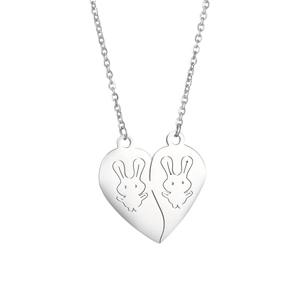 Detail of interlocking heart pendants with engraved cartoon rabbits on steel necklaces