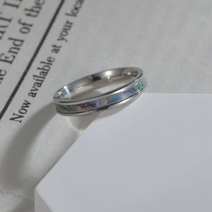 Polished 4mm titanium steel ring with iridescent shell inlay on white geometric stand