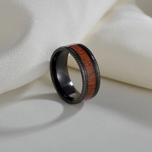 Macro view of black titanium ring featuring a natural acacia wood inlay and stepped edges