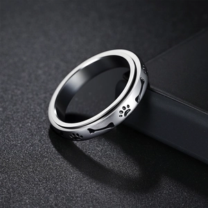 Polished 4mm stainless steel spinner ring with engraved black paw prints and bones
