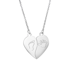 Macro detail of stainless steel heart puzzle necklace with baby hand and footprint engraving
