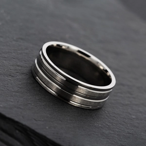 Detailed view of silver stainless steel rings on black rock background with brushed finish