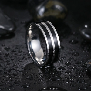 Detail of 8mm men's stainless steel ring with black enamel stripes on a pebble background