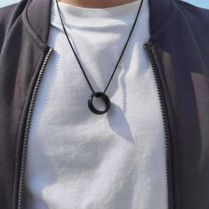Collier minimaliste noir en acier inoxydable avec pendentif cercle sur un t-shirt blanc