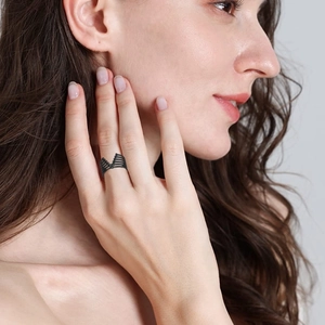 Dettaglio di un anello geometrico in acciaio al titanio nero traforato a forma di V sul dito