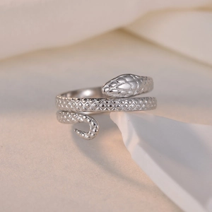 Adjustable silver snake ring with scale texture shown on a minimalist prop background