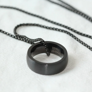 Gros plan d'un pendentif bague en carbure de tungstène noir mat sur une chaîne à perles