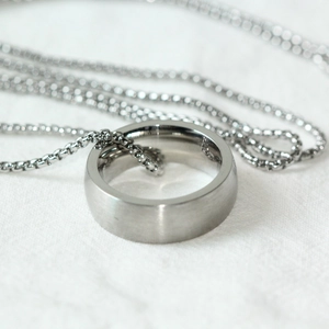 Détail macro d'une bague en argent brossé avec chaîne boîte minimaliste sur fond blanc