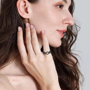 Détail d'une bague géométrique noire moderne au doigt d'un mannequin avec une finition mate