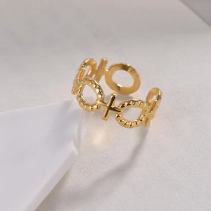 Bague ajustable en acier doré motif XO polie présentée sur un décor de pierre blanche
