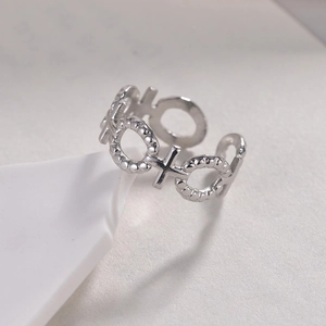 Bague ajustable en acier titane avec motif XO ajouré sur fond blanc épuré