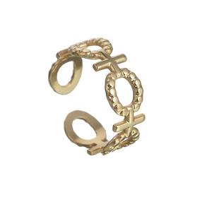 Détail d'une bague réglable en titane plaqué or avec motifs X et O et bordure perlée délicate