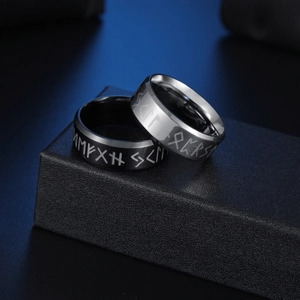 Set of black and silver stainless steel Viking rune rings on a textured jewelry box