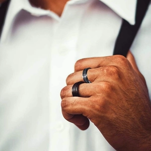 Men's matte black titanium ring set featuring one brushed finish and one engraved pattern