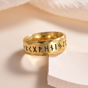 Close-up of golden Viking rune ring with hammered texture and engraved Nordic symbols