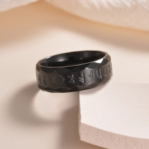 Macro detail of black titanium ring with Nordic runes and industrial hammered texture