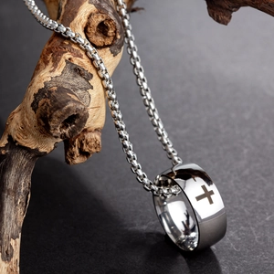 Polished stainless steel cross pendant necklace hanging on a natural wooden branch