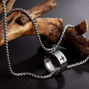 Detailed close-up of hollow cross ring with silver box chain on wooden stand