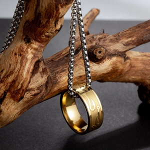 Titanium steel necklace and gold ring with fishhook engraving on a dark stone background