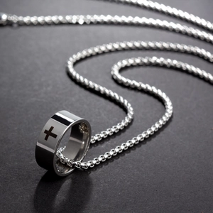 Macro shot of silver stainless steel ring with black cross engraving on a box chain