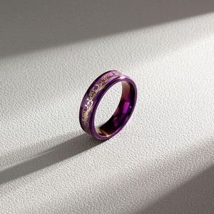 Macro shot of purple titanium steel ring with golden dragon engraving on grey leather