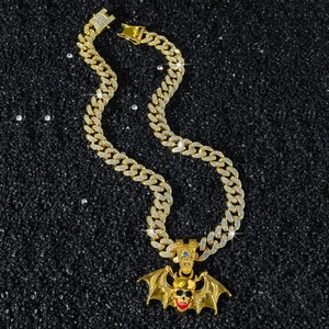 Iced out gold Cuban chain necklace with a bat skull pendant featuring red lip accents