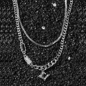 Collier double rang argenté avec pierres noires et pendentif étoile sur sable minéral noir