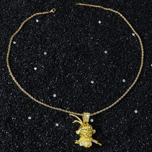Détail du pendentif Sun Wukong doré serti de zircons sur fond de pierres sombres