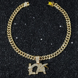 Vue détaillée de la chaîne cubaine dorée avec pendentif lettre LA glacé