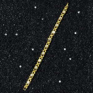 Dettaglio di un bracciale a catena dorata da 8mm con maglie X-O e cristalli lucenti