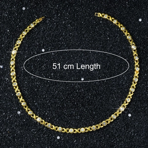 Detail view of 51cm gold XO chain necklace with clear zircons on black sand background