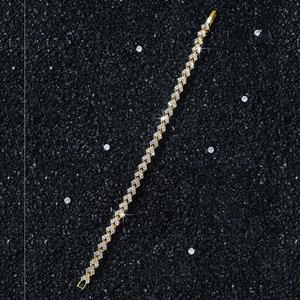 Macro shot of gold tennis bracelet with white cubic zirconia on black sand background
