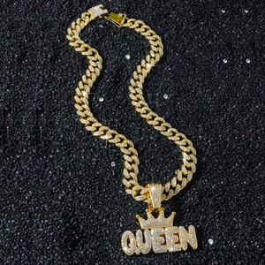 Hip-Hop Goldkette mit vereistem QUEEN-Kronenanhänger auf schwarzem Sandhintergrund