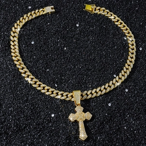 Gros plan détaillé d'un collier chaîne cubaine dorée avec pendentif croix serti de strass